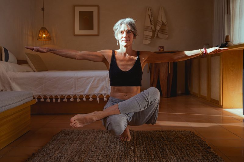 An older adult doing a gentle balance exercise in a bright room